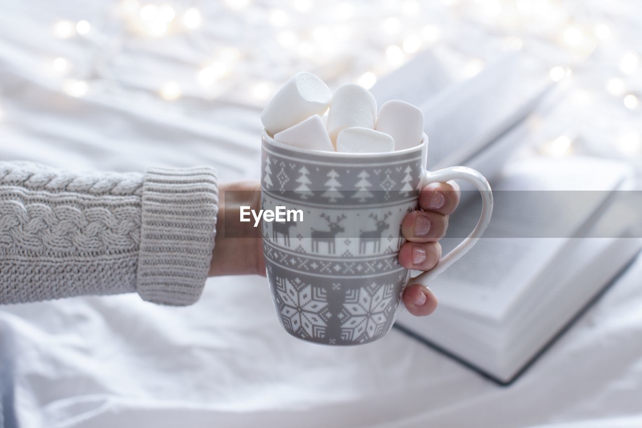 HIGH ANGLE VIEW OF HAND HOLDING WHITE CUP