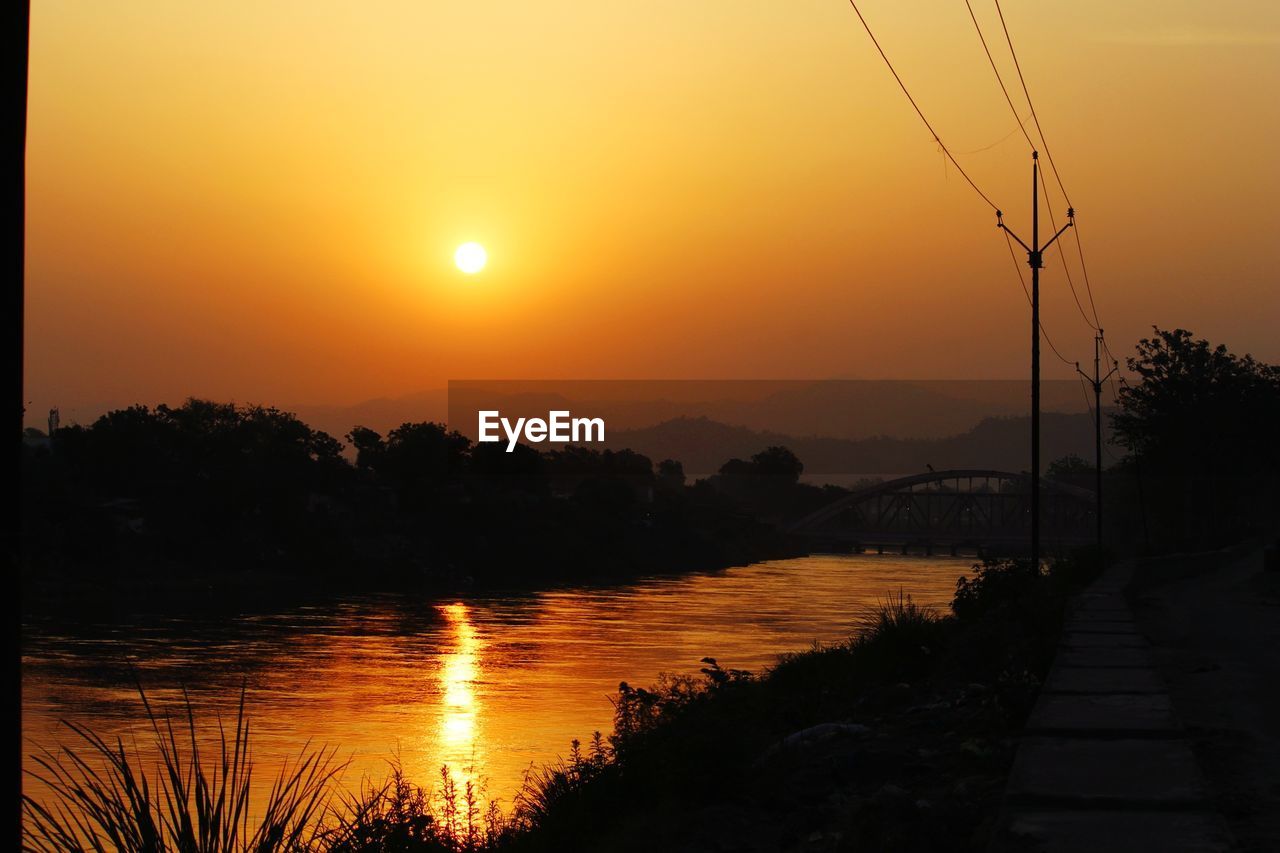 SCENIC VIEW OF LAKE AGAINST ORANGE SKY AT SUNSET