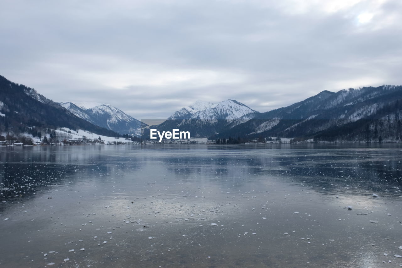 Scenic view of lake by snowcapped mountains against sky