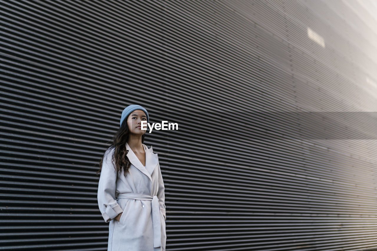 Thoughtful woman in front of black corrugated wall