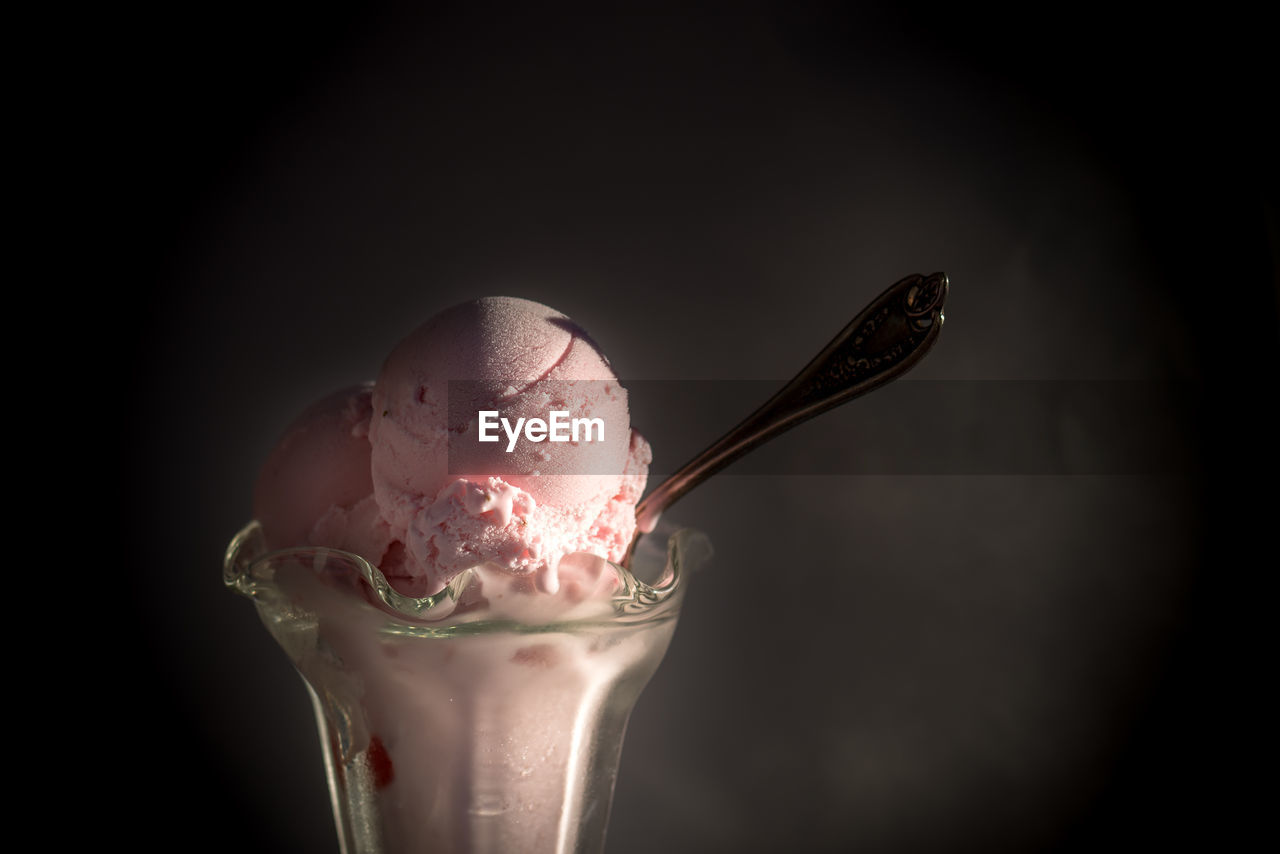 CLOSE-UP OF ICE CREAM ON GLASS AGAINST BLACK BACKGROUND