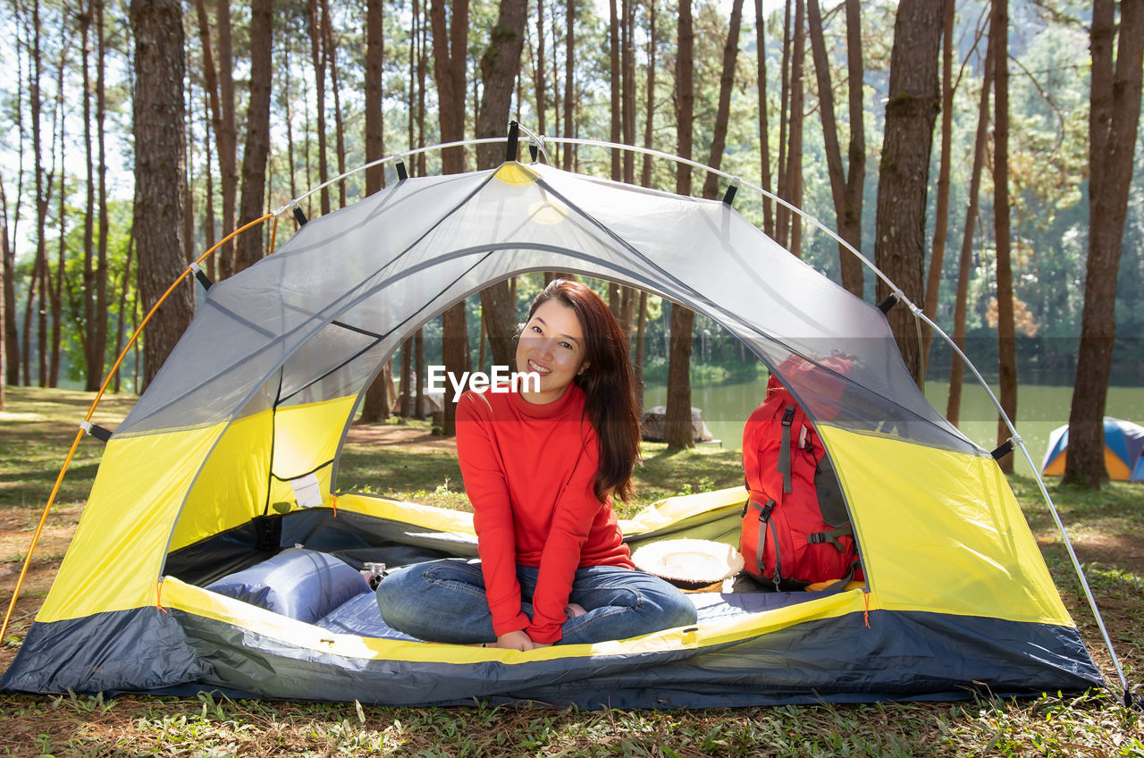 Woman camping, sitting in a tent forest beside a lake, pang oung, mae hong son, thailand.