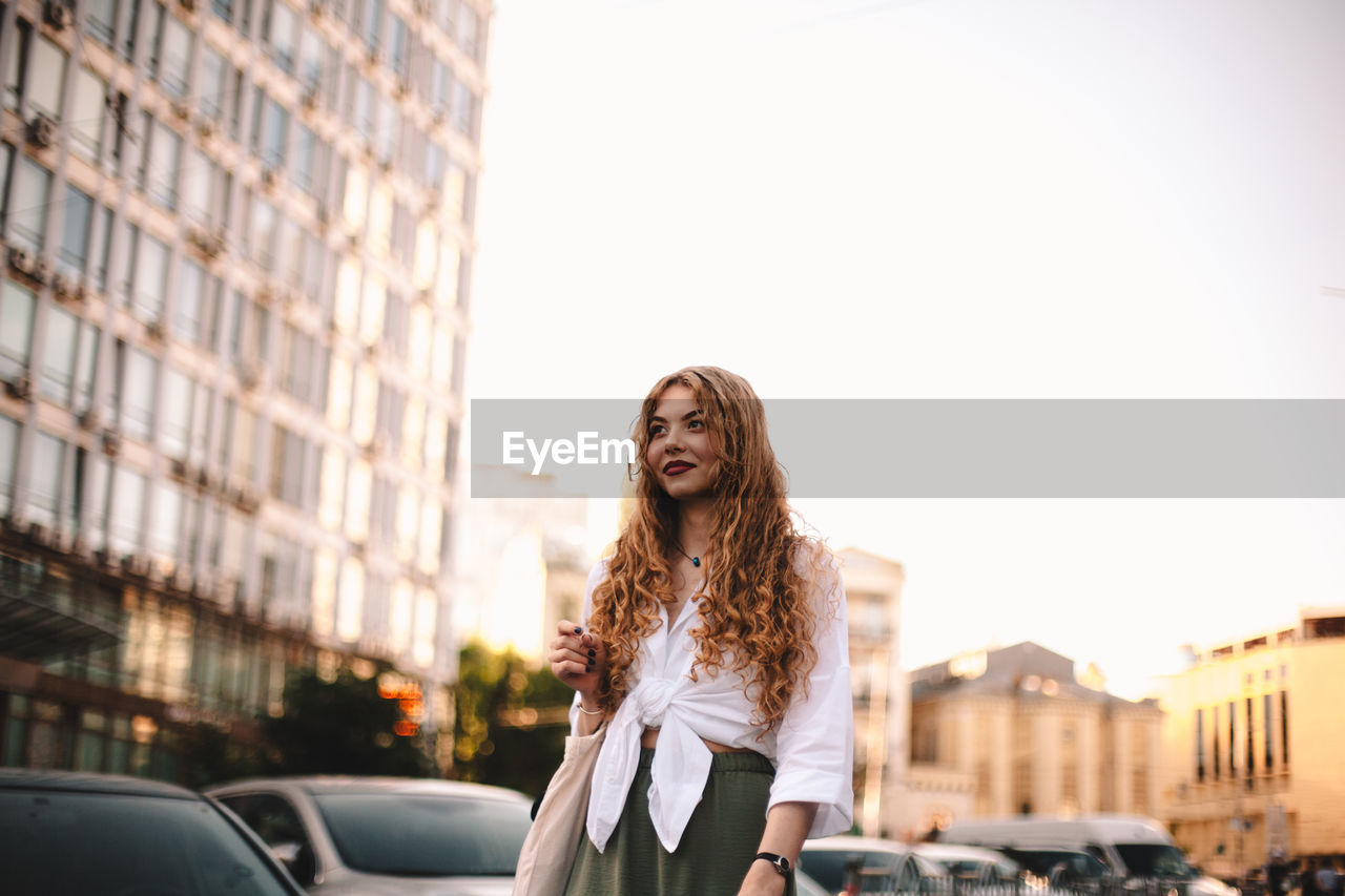 Thoughtful young woman walking on street in city during summer