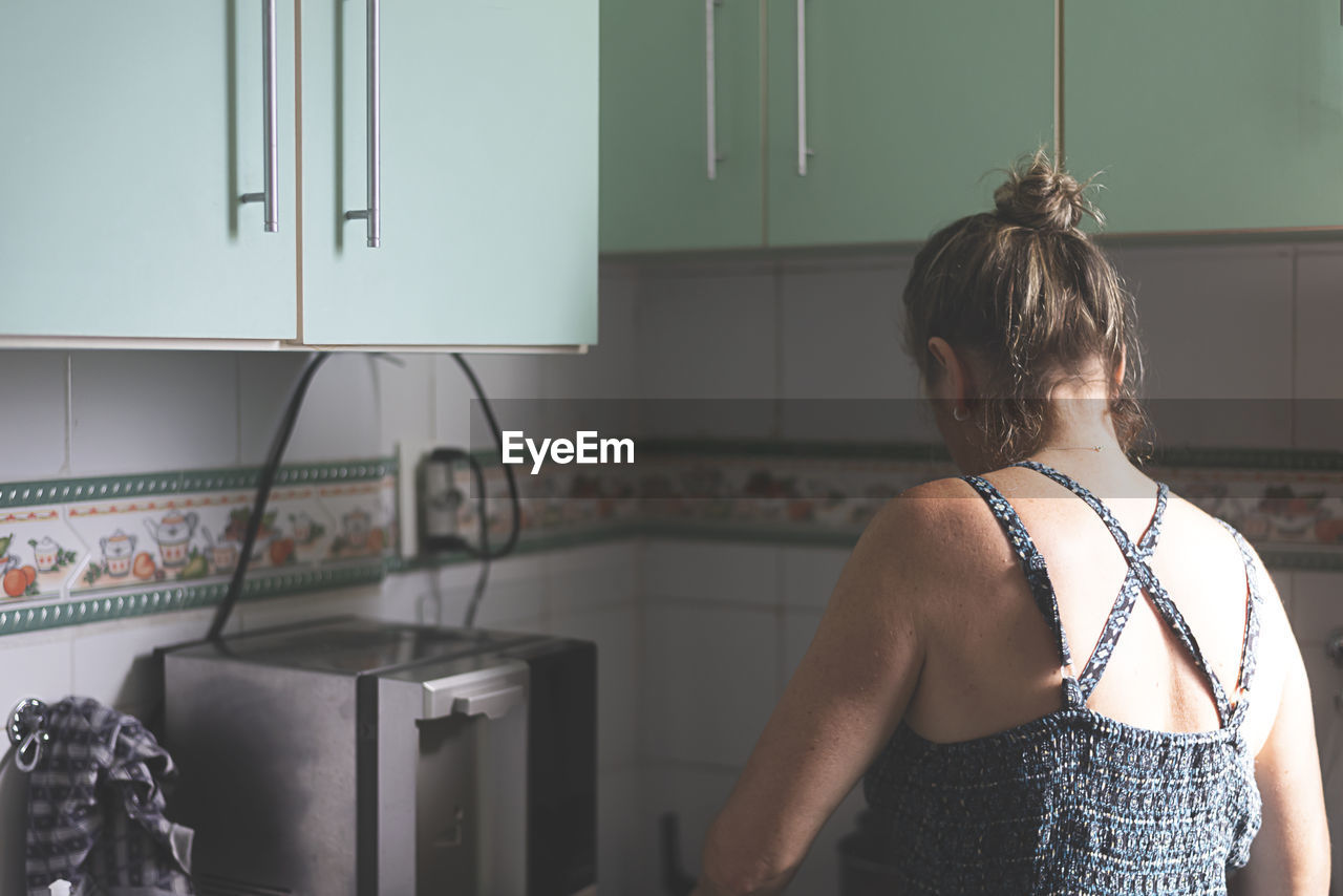 Caucasian woman with her back to her cooking in the kitchen. 