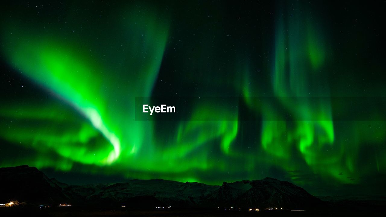 Aurora polaris over mountains against sky at night