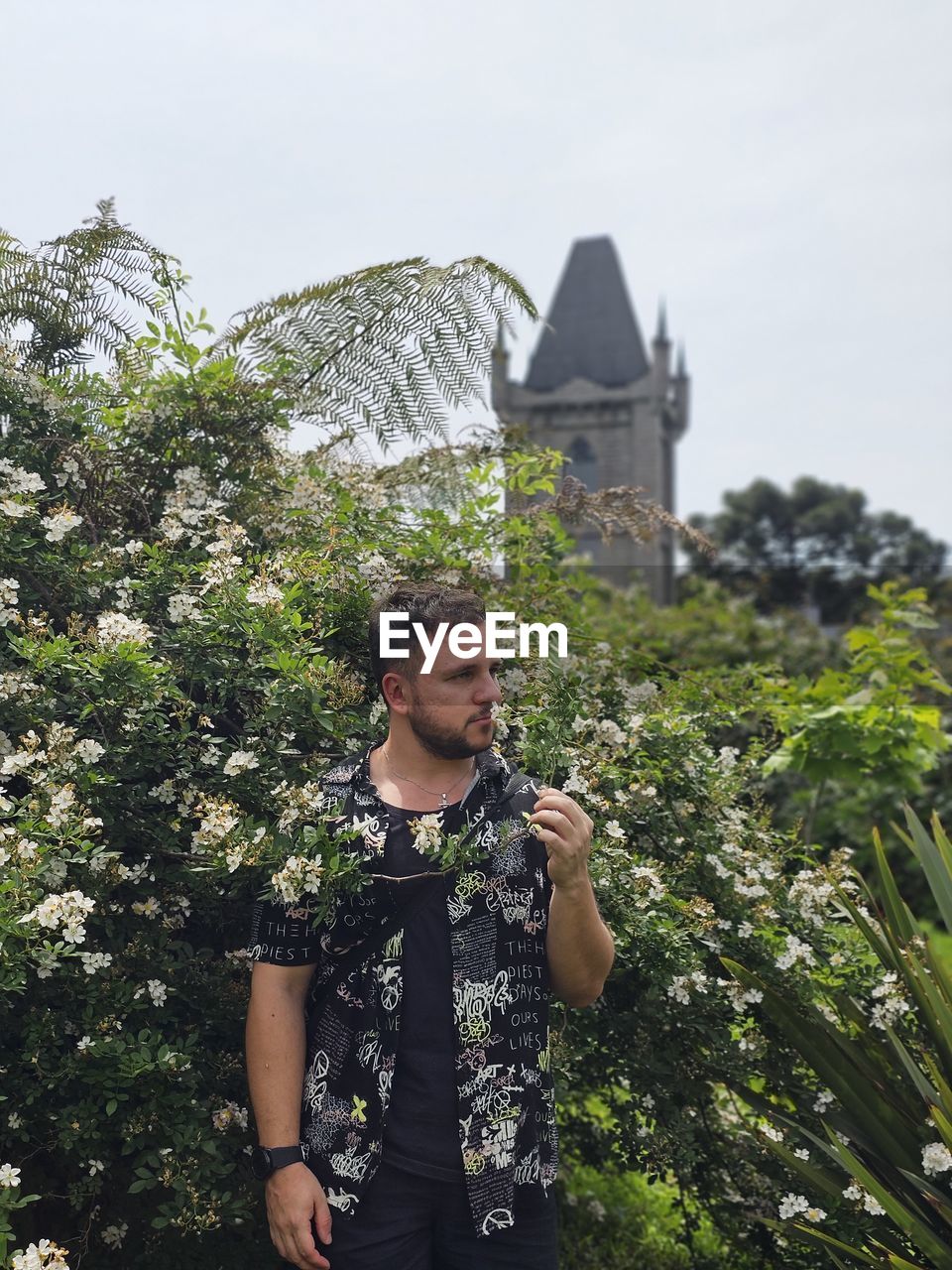 Low section of man holding plant in a garden in front of a castle