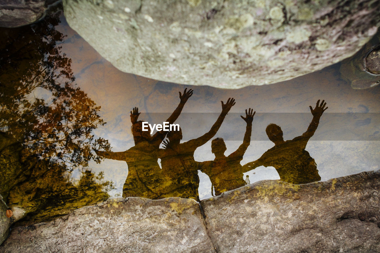 Reflection of friends in water on rock formation