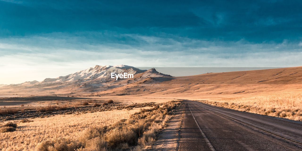 Road amidst desert against sky