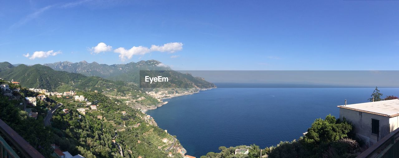 High angle view of sea and mountains against blue sky