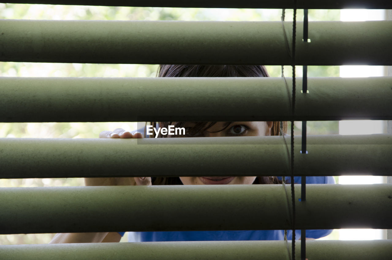 Woman looking through window blinds