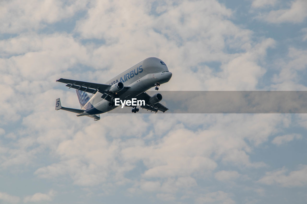 LOW ANGLE VIEW OF AIRPLANE AGAINST CLOUDY SKY