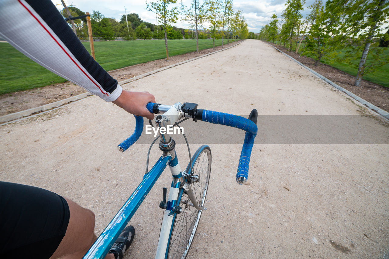 MAN RIDING BICYCLE ON ROAD BY FENCE