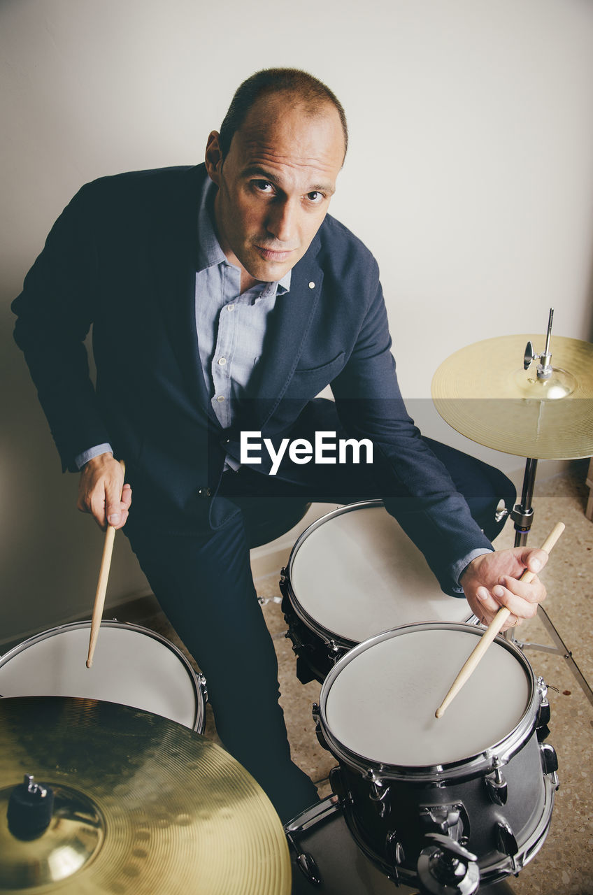 Portrait of confident drummer playing drums