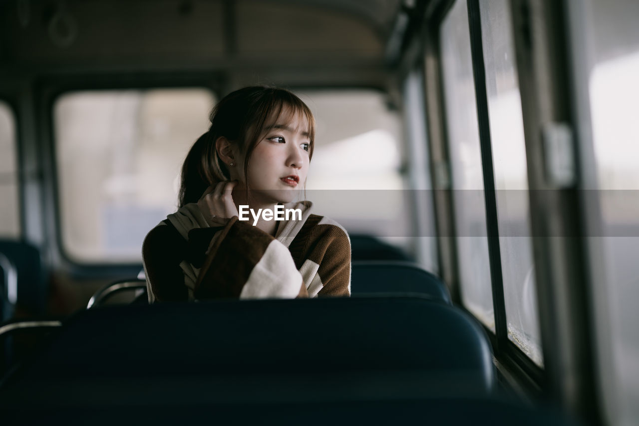 portrait of young woman sitting in train