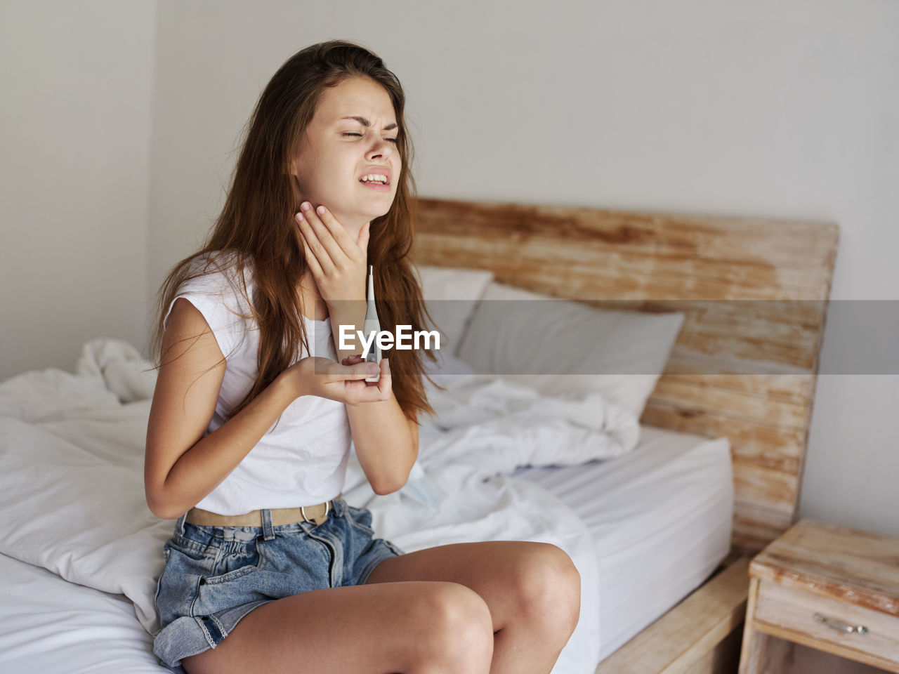 Beautiful young woman sitting on bed at home