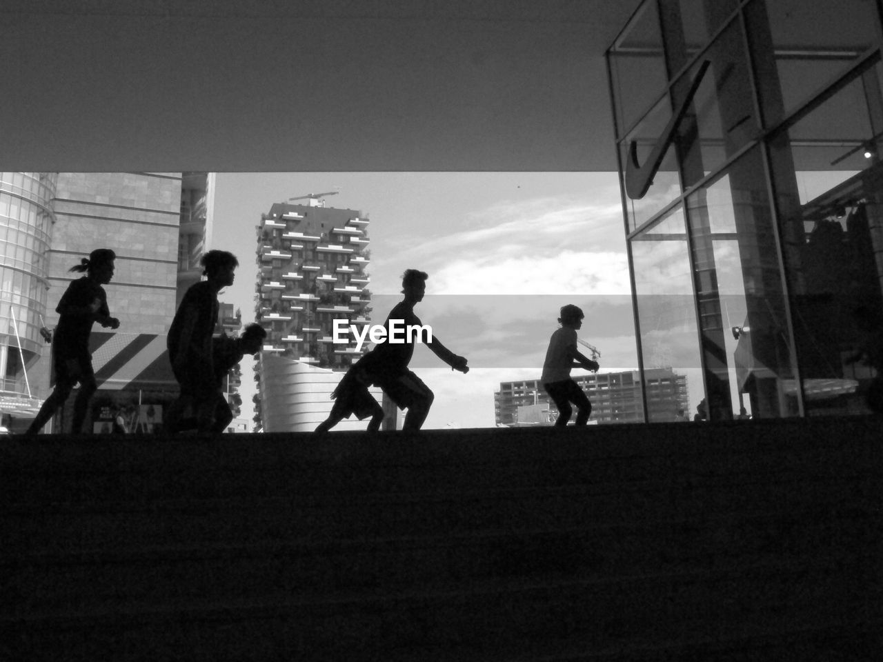 Silhouette boys dancing with buildings in background