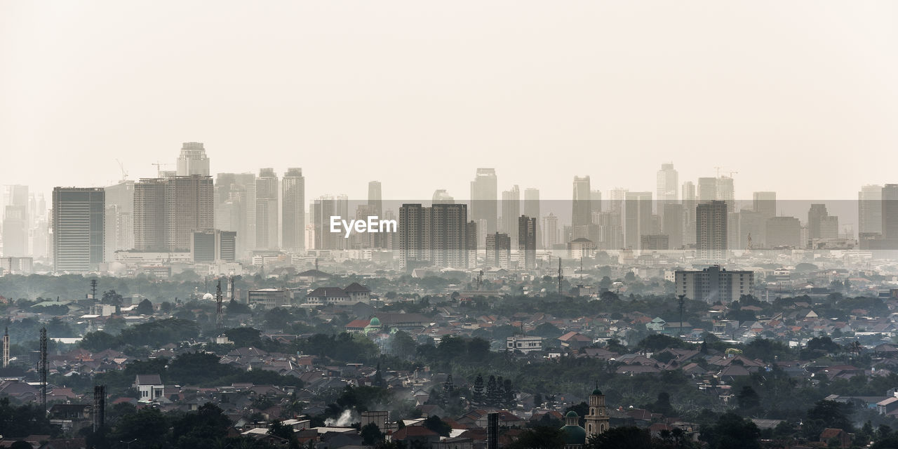 Aerial view of buildings in city against clear sky