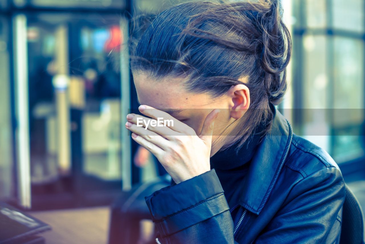 Close-up of woman covering eyes