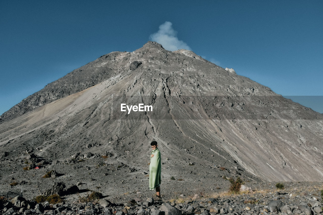 Full length of boy standing against volcano