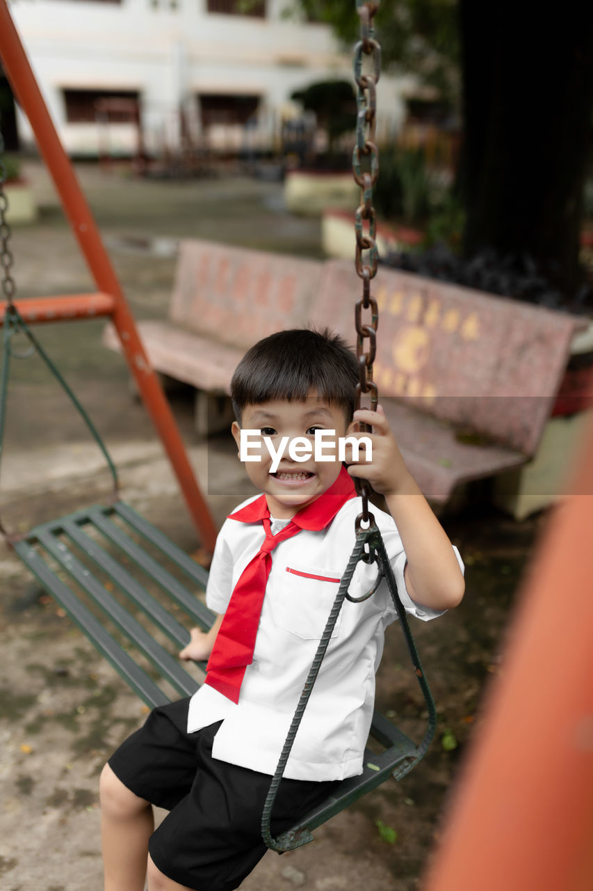 Portrait of cute boy sitting on swing