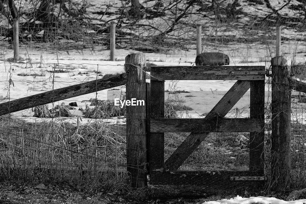 Old wooden gate on field during winter