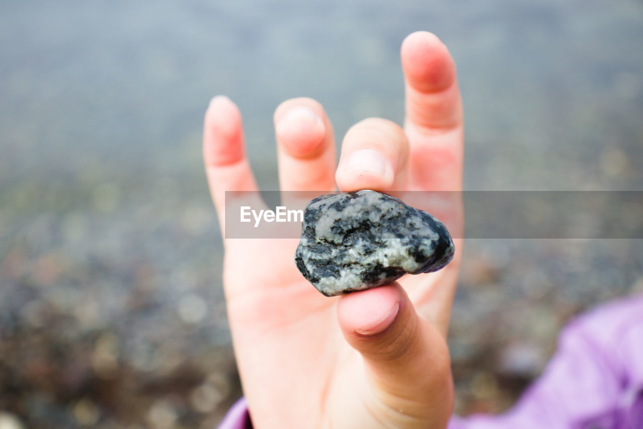 CLOSE-UP OF HUMAN HAND HOLDING ROCK