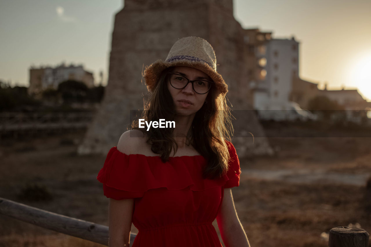 Portrait of woman standing in city against sky