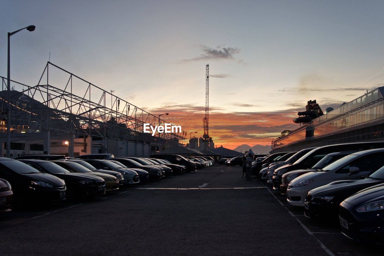 Cars parked at parking lot against sky during sunset