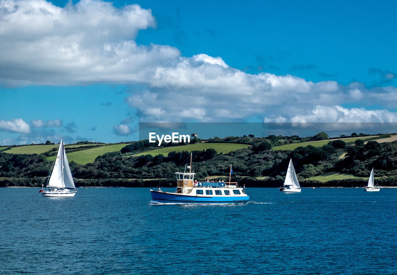 BOATS SAILING ON SEA AGAINST CLOUDY SKY