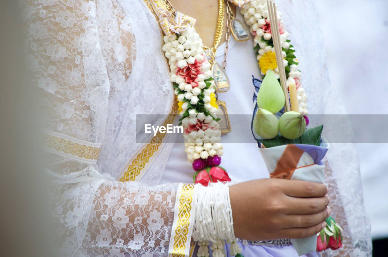 Midsection of bride wearing floral garland