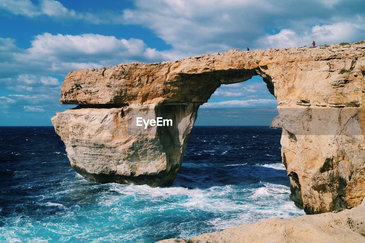 Scenic view of rock formation in sea against sky