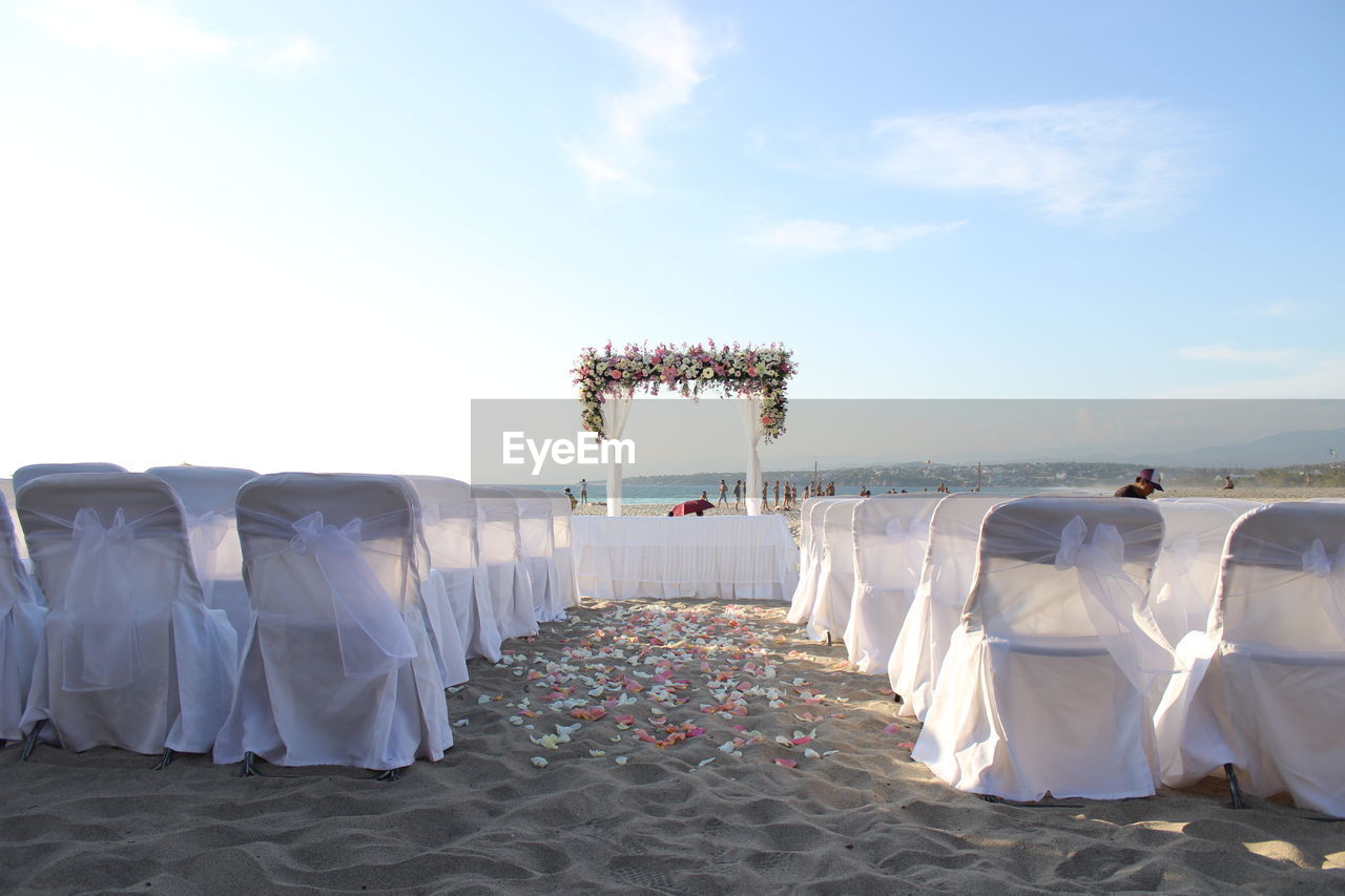 Chairs arranged at beach for wedding ceremony