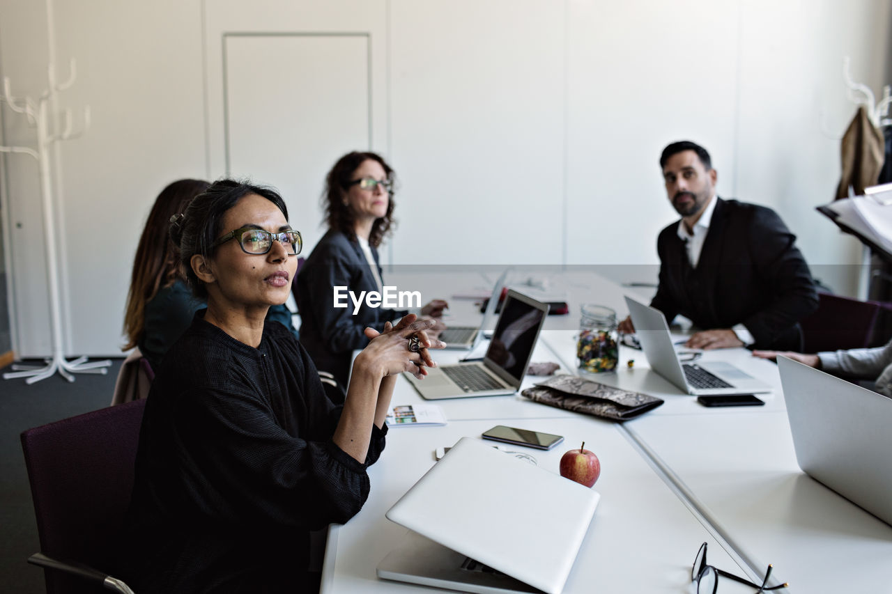 Business people sitting at conference table concentrating during meeting in board room