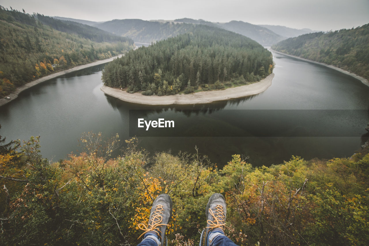 Low section of person flying over river