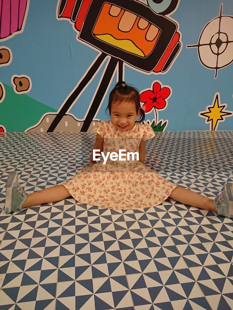 Portrait of cheerful girl sitting on patterned floor