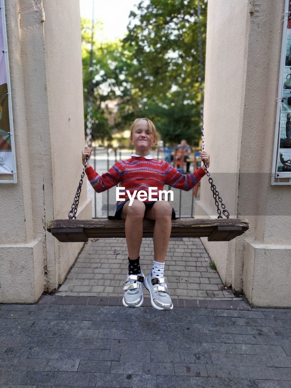 Full length portrait of smiling girl sitting on swing outdoors