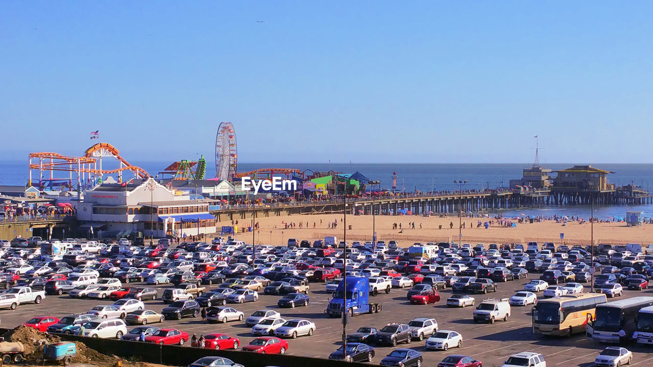 People in amusement park by sea against clear sky