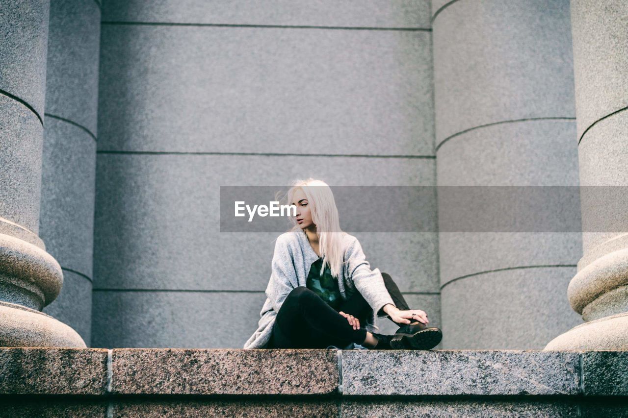 WOMAN SITTING WITH UMBRELLA IN CITY