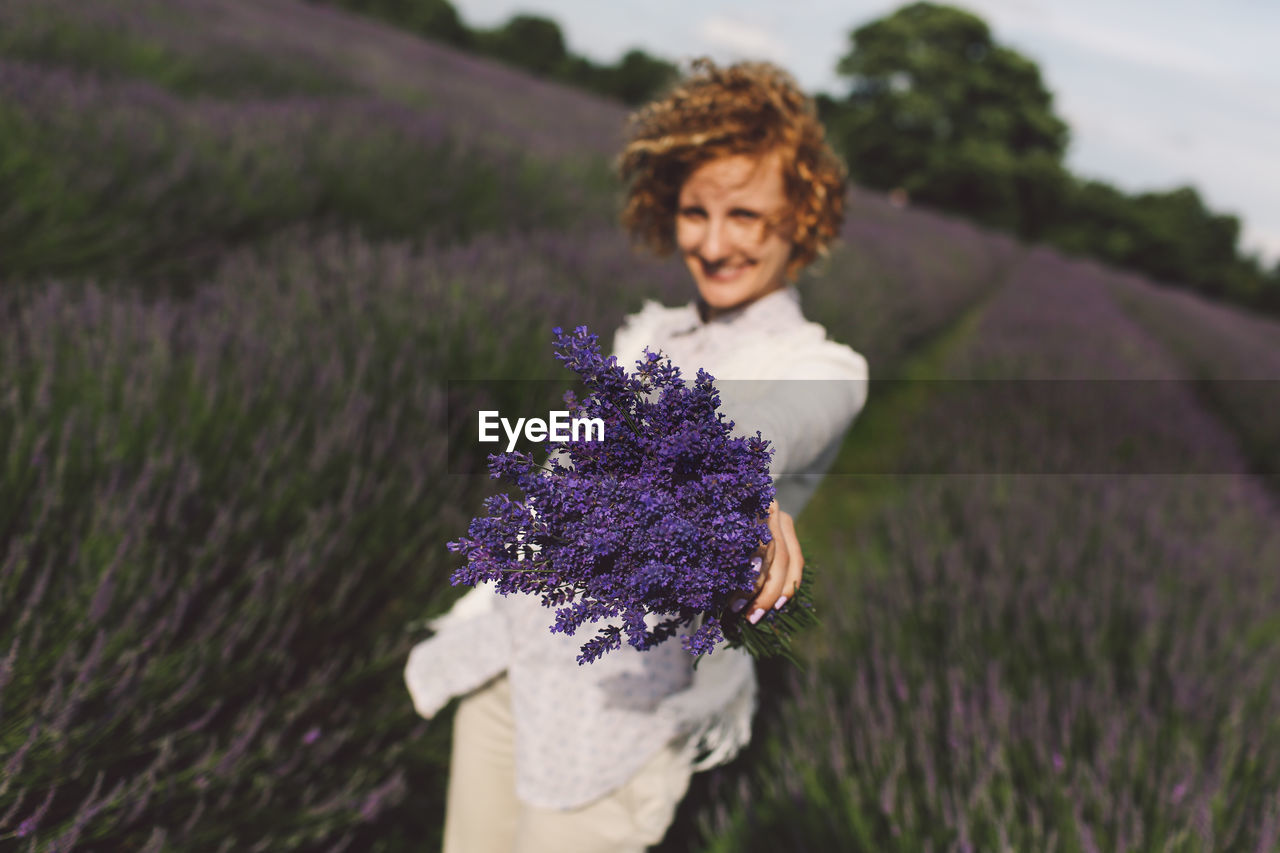 Portrait of happy woman holding lavender bouquet field