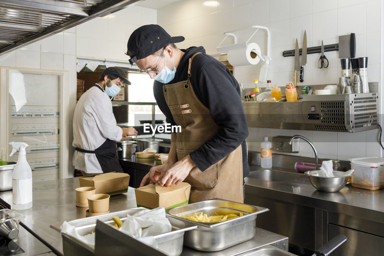 Chefs preparing takeaway food in kitchen at restaurant