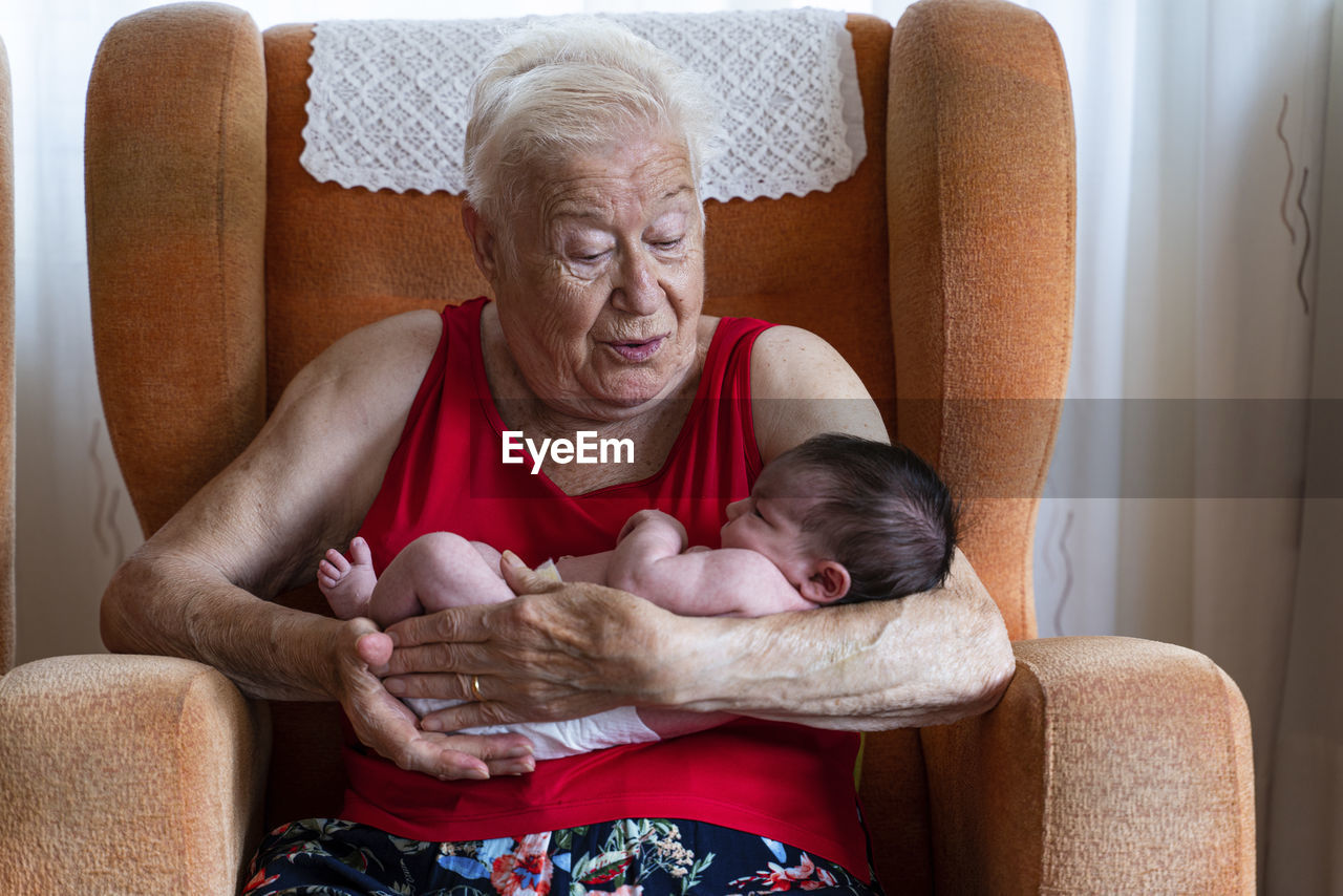 Grandmother holding her newborn baby granddaughter at home