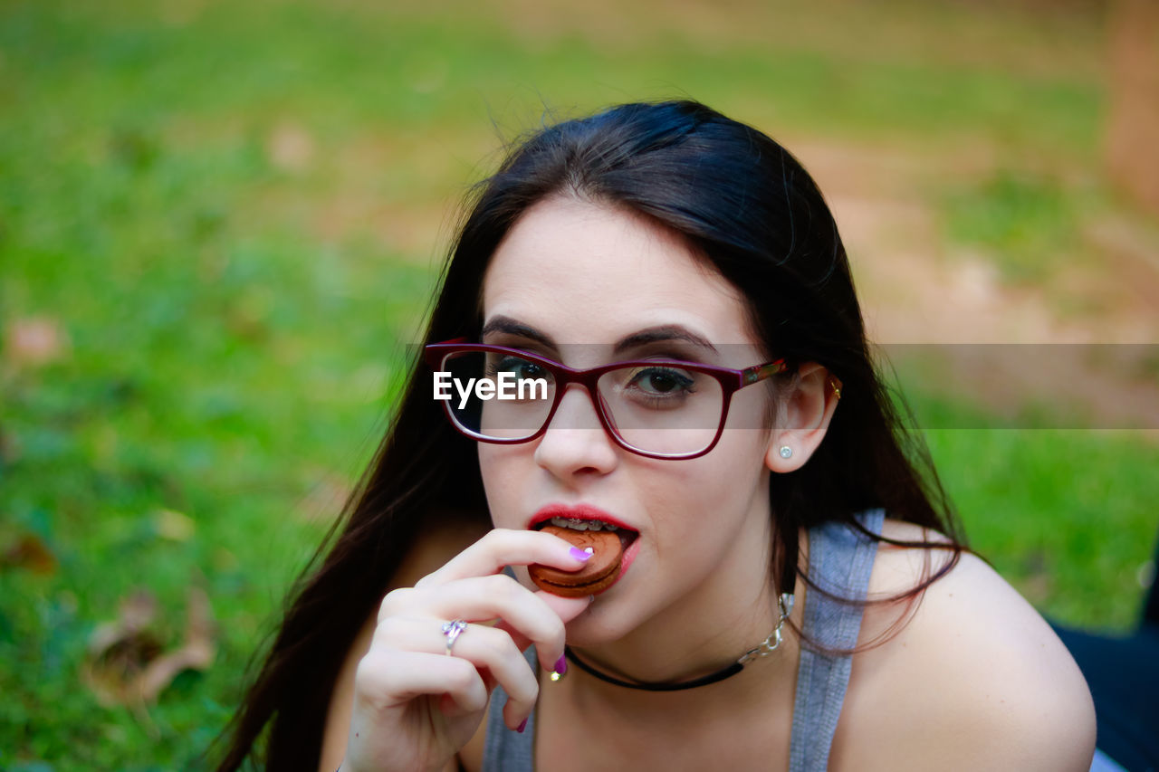 Close-up portrait of young woman eating biscuit outdoors