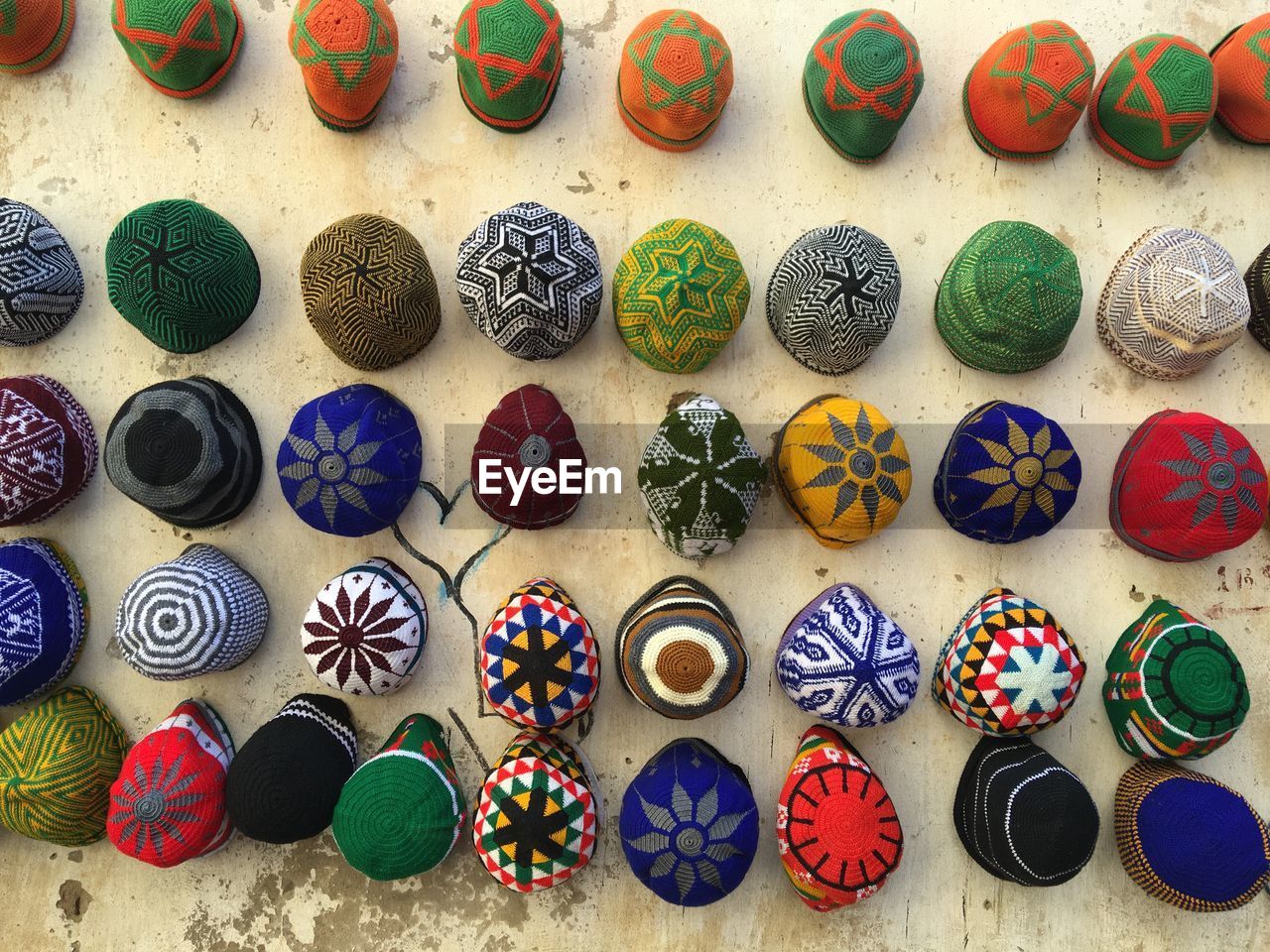 Close-up of multi colored skull caps hanging on wall for sale