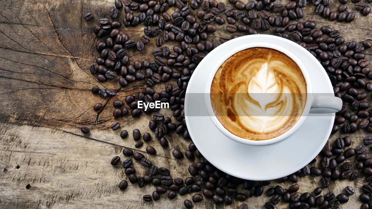 Cappuccino and roasted coffee beans on table