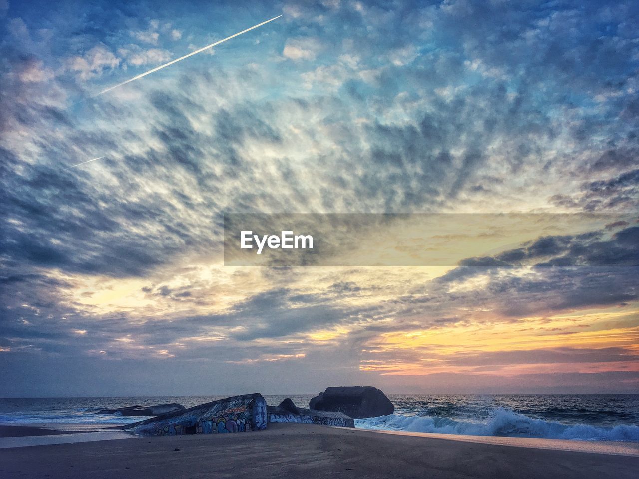 Scenic view of beach against cloudy sky