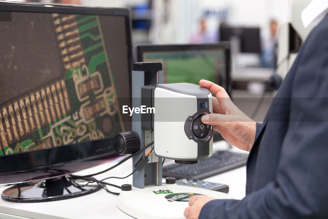 CLOSE-UP OF MAN USING MOBILE PHONE IN OFFICE