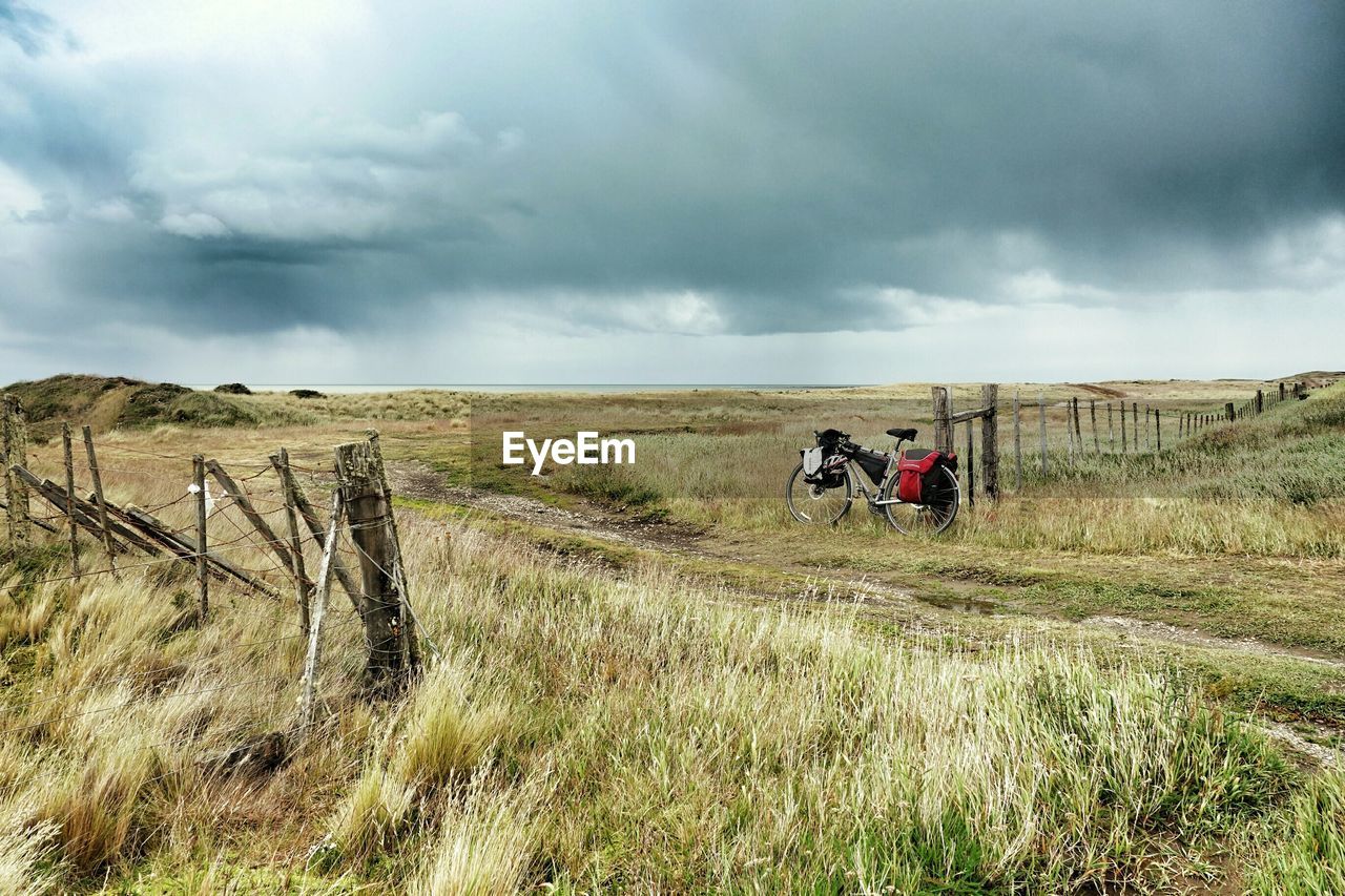 Bicycle leaning against fence in field