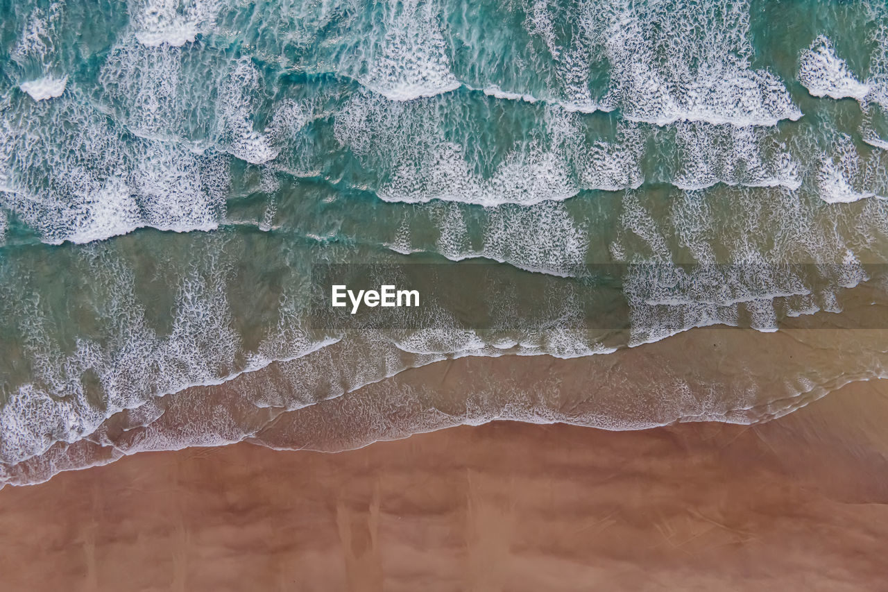 Aerial drone view of the waves on the sand beach