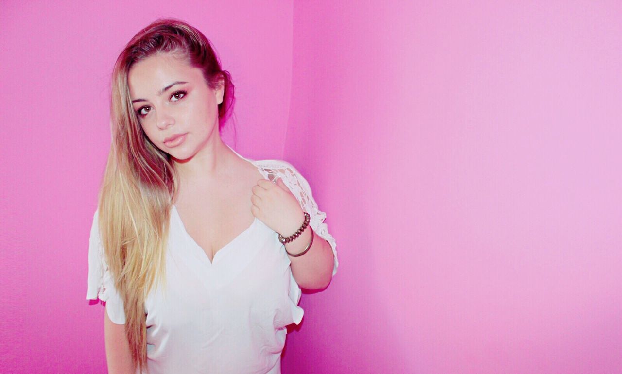 Portrait of beautiful woman standing against pink wall