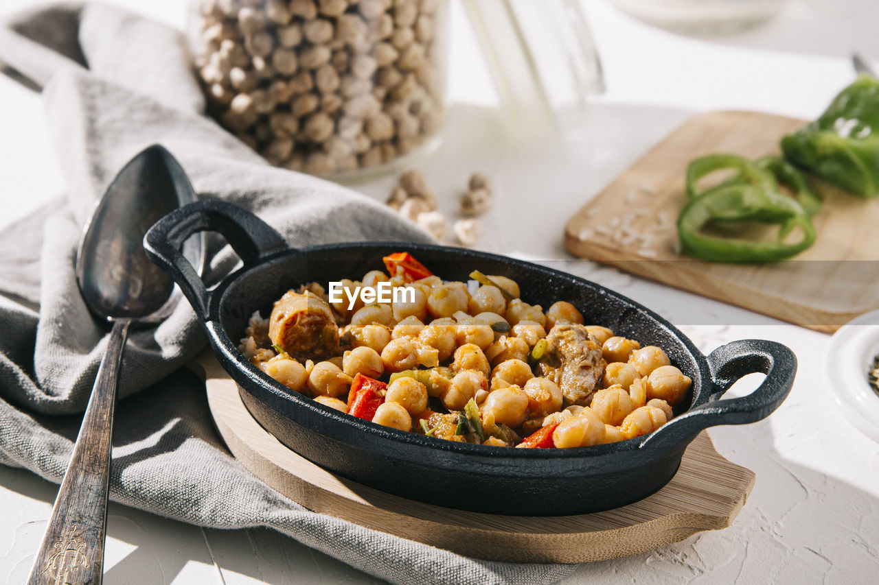 Chickpea stew with ingredients in background on table